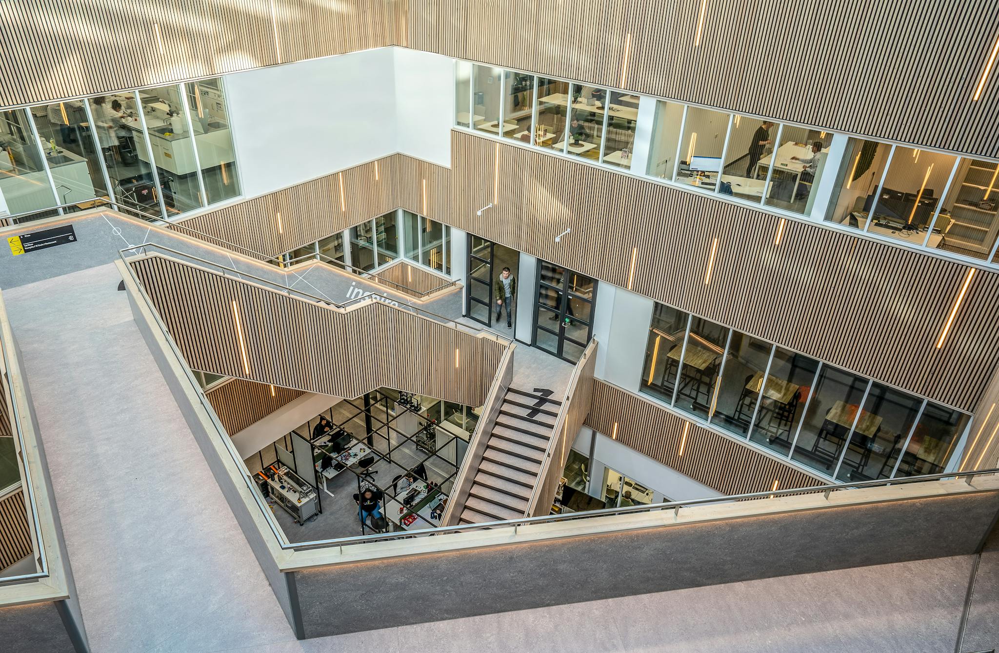 Spacious atrium in a contemporary office building with wooden panels and staircases.